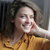 A woman smiling while seated in front of a window